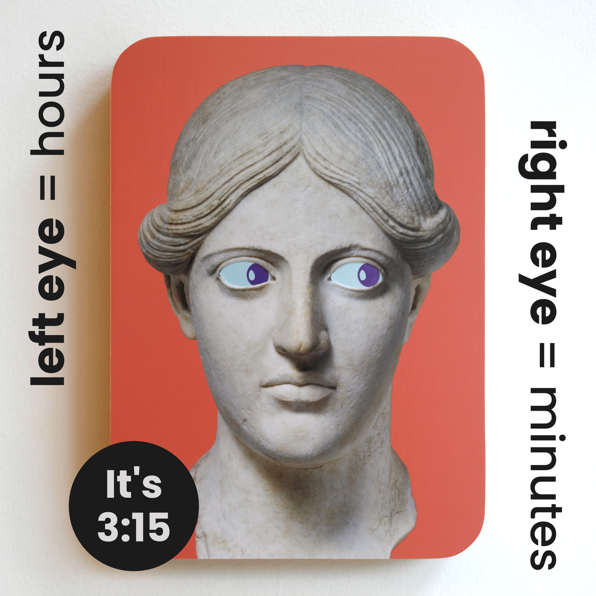 A printed statue head on a red rectangular background with blue eyes and purple pupils that both look to the right. Image text: ‘Left eye = hours. Right eye = minutes. It’s 3:15.’