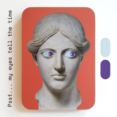 A unique art clock made of a printed statue head with blue and purple eyes on a pink rectangular background. One eye is looking up, the other is looking down. Image text: ‘Psst... my eyes tell the time'.