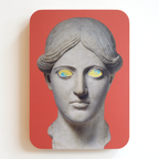 A printed statue head on a pink rectangular background with yellow eyes and blue pupils. One eye is looking up, the other eye is looking down.