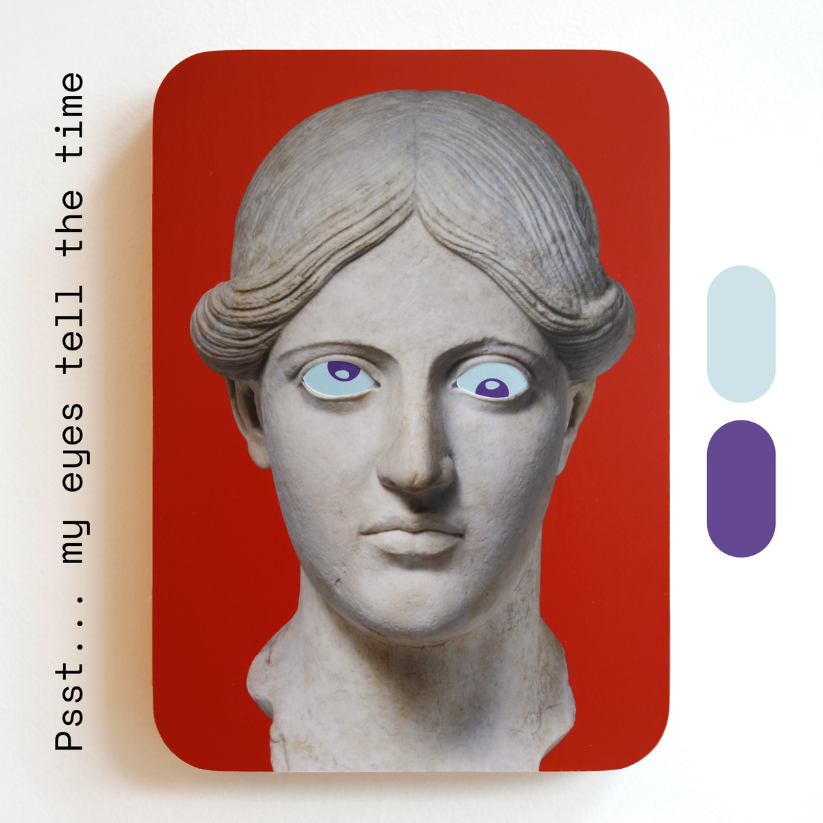 A unique art clock made of a printed statue head with blue and purple eyes on a red rectangular background. One eye is looking up, the other is looking down. Image text: ‘Psst... my eyes tell the time'.
