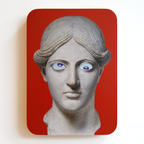 A printed statue head on a red rectangular background with blue eyes and purple pupils. One eye is looking up, the other eye is looking down.