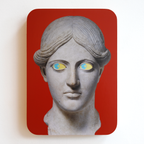 A printed statue head on a red rectangular background with yellow eyes and blue pupils that both look to the left.